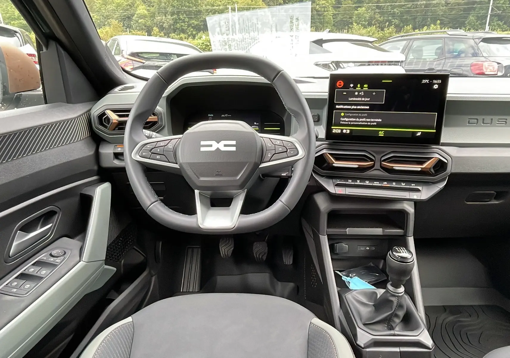Vue intérieure avant du Dacia Duster 2025, volant cuir et tableau de bord avec écran tactile central.