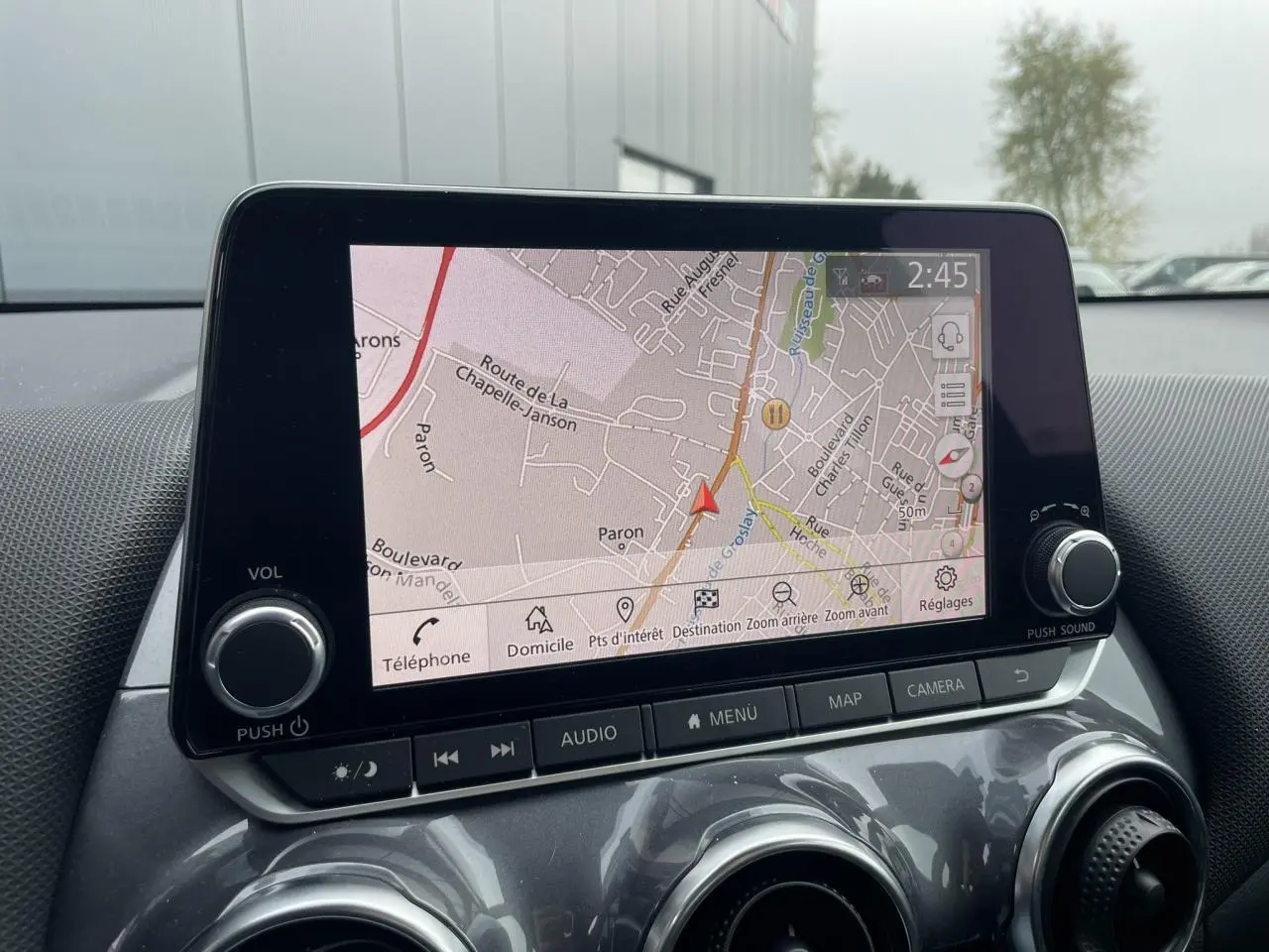 Écran tactile 8 pouces du Nissan Juke 2024 affichant la navigation, vu de face dans l'habitacle gris.
