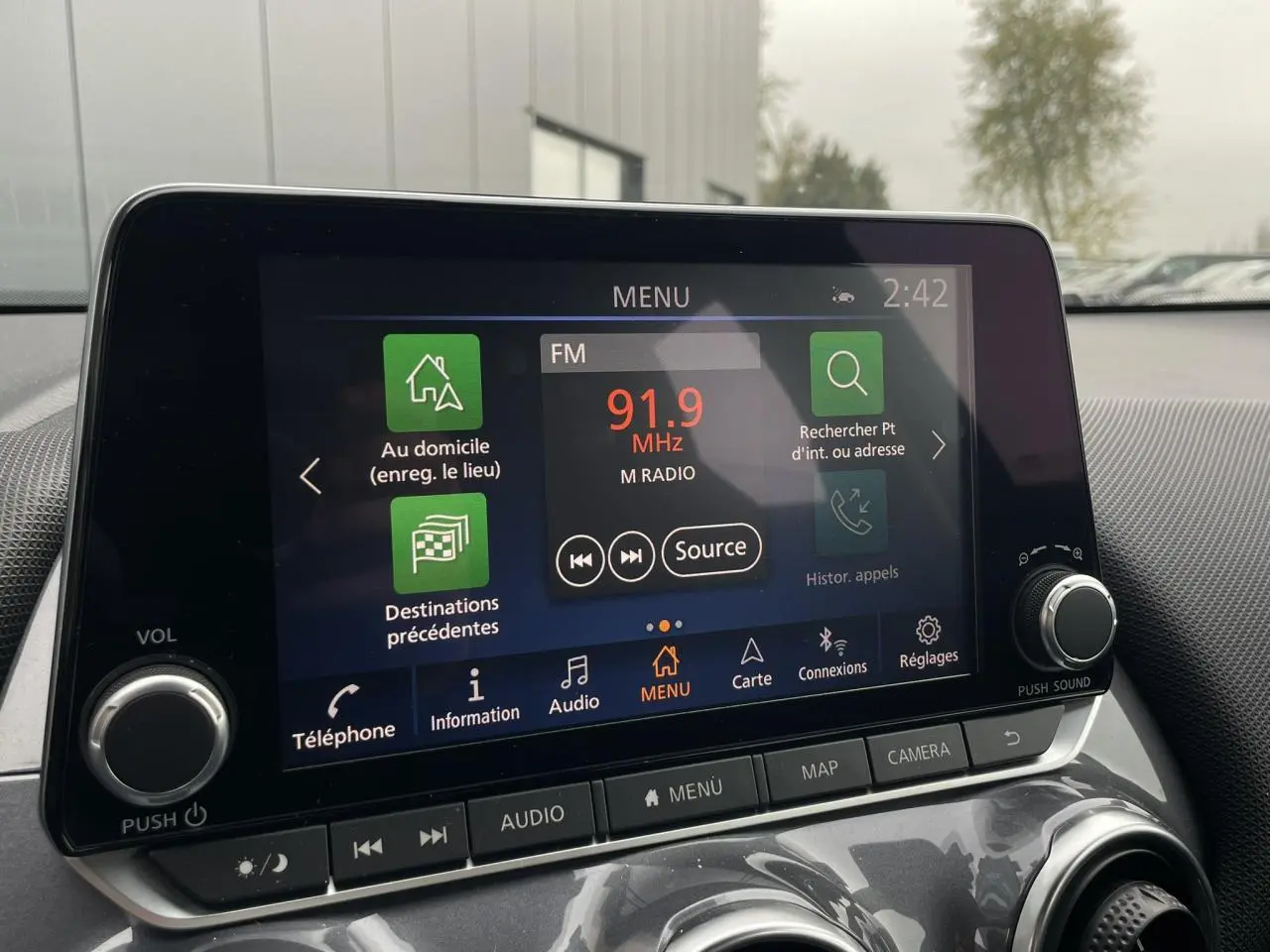 Écran tactile central du Nissan Juke 2024 affichant la radio FM à 91,9 MHz dans un intérieur gris.