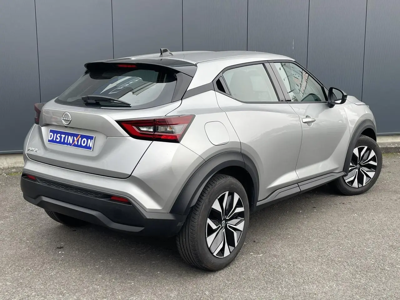 Vue 3/4 arrière droite d'un Nissan Juke gris silver 2024 avec feux LED et jantes distinctives.