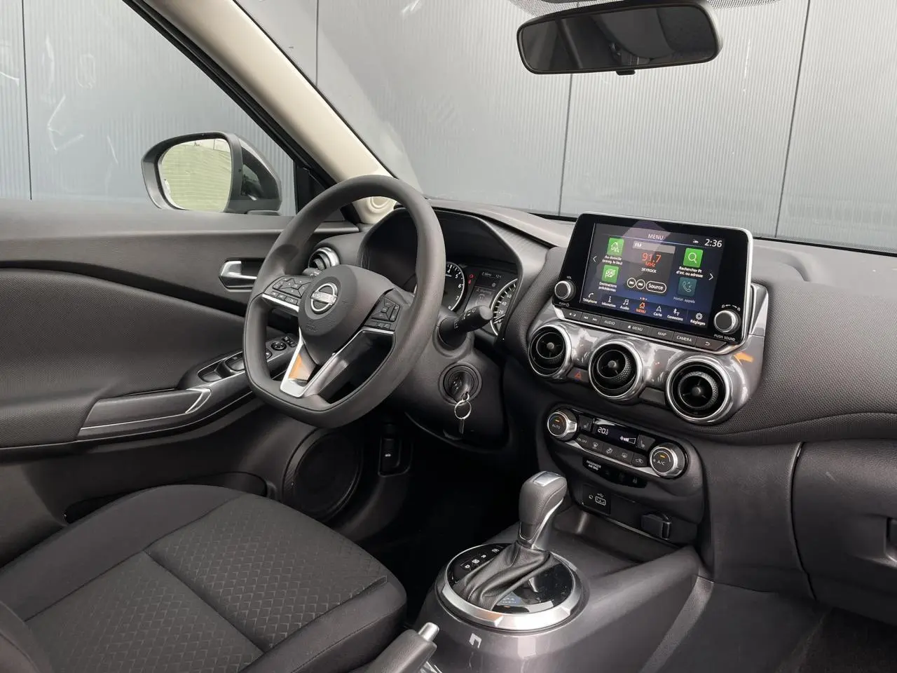 Intérieur du Nissan Juke 2024 côté conducteur, tableau de bord noir avec écran tactile et boîte automatique.