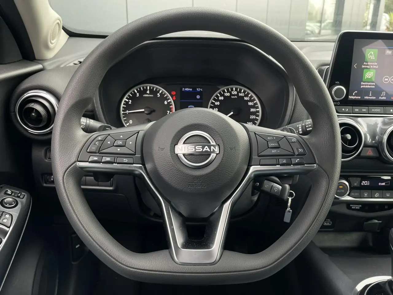Vue rapprochée du volant multifonction noir du Nissan Juke 2024 avec tableau de bord et écran tactile visible à droite.