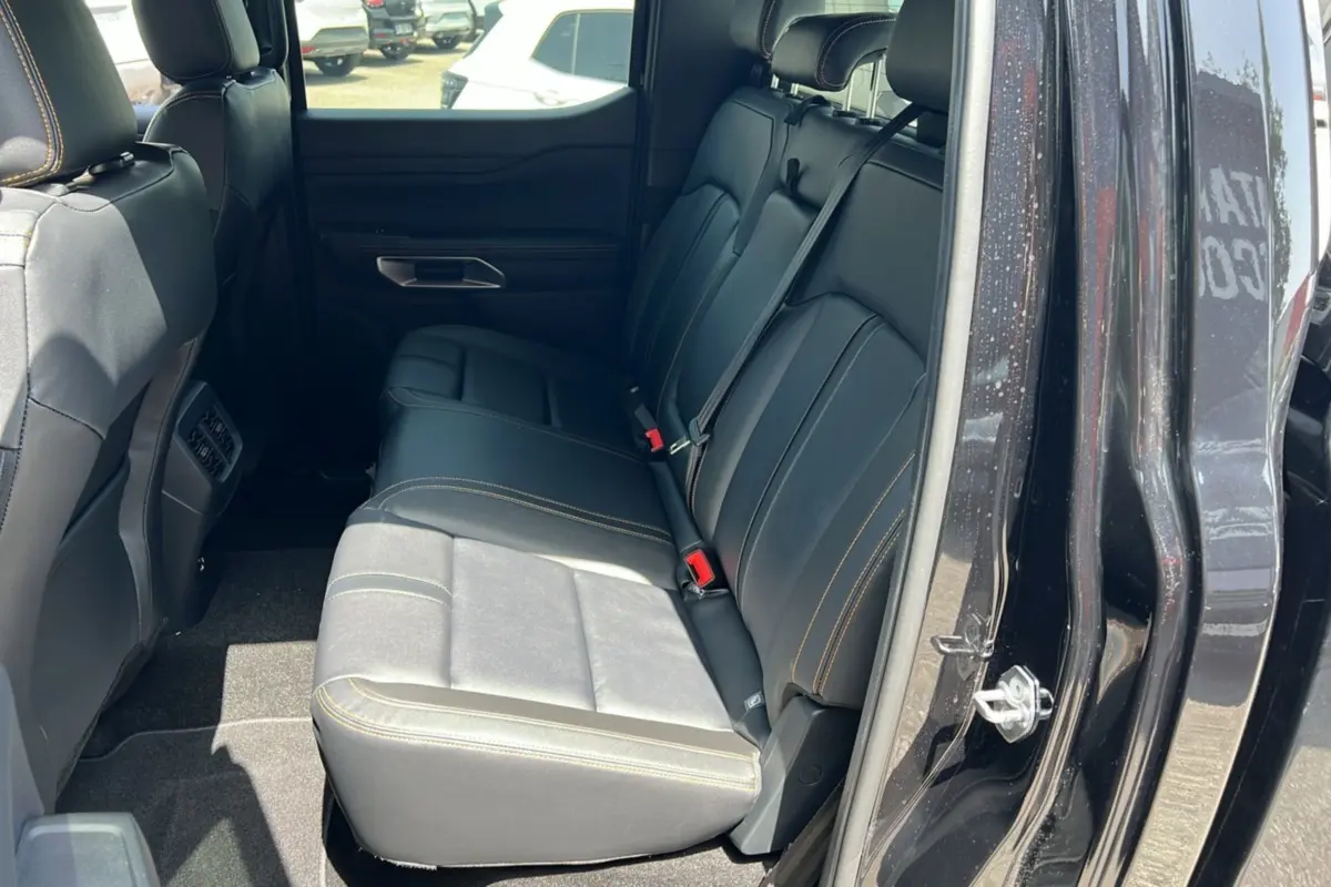 Vue intérieure côté droit sur la banquette arrière en cuir noir avec surpiqûres orange du Ford Ranger Wildtrak Plus 2025.