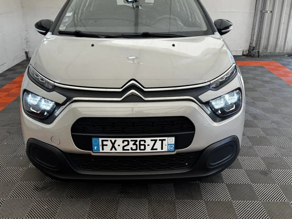 Vue avant d'une Citroën C3 beige 2021 avec phares LED allumés et calandre noire distinctive.