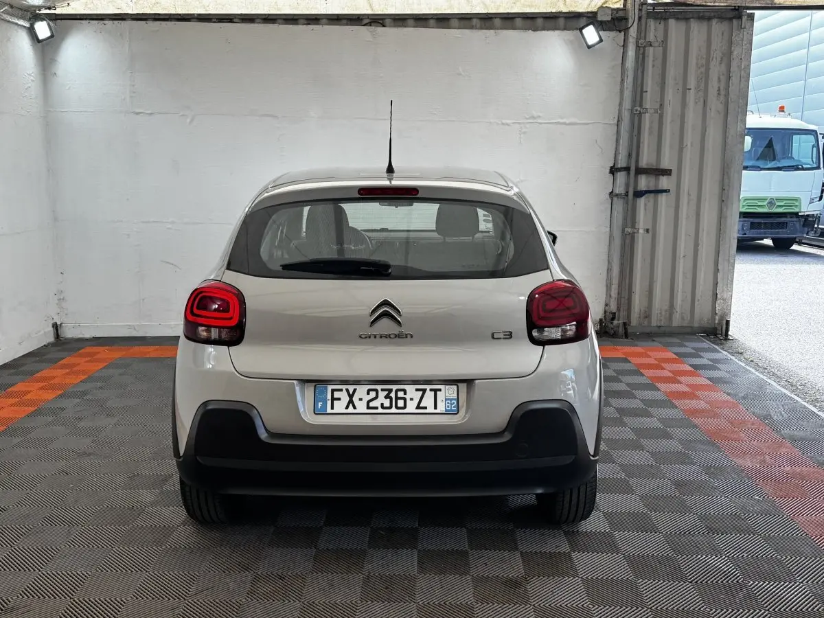 Vue arrière d'une Citroën C3 beige 2021 stationnée dans un garage avec plaques d'immatriculation françaises visibles.