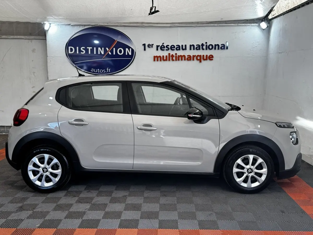 Vue latérale droite d'une Citroën C3 beige 2021 avec protections noires et jantes alliage en showroom.