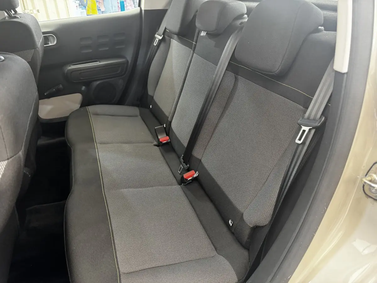 Vue intérieure côté droit sur la banquette arrière noire et grise de la Citroën C3 beige, avec ceintures de sécurité visibles.
