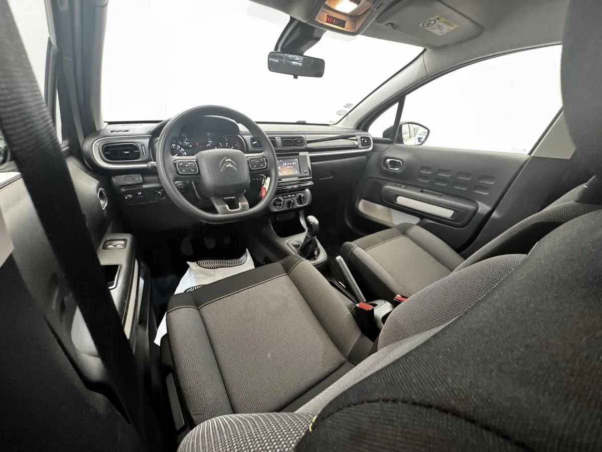 Vue intérieure avant de la Citroën C3 2021, sièges gris, tableau de bord avec volant multifonctions et écran tactile central.