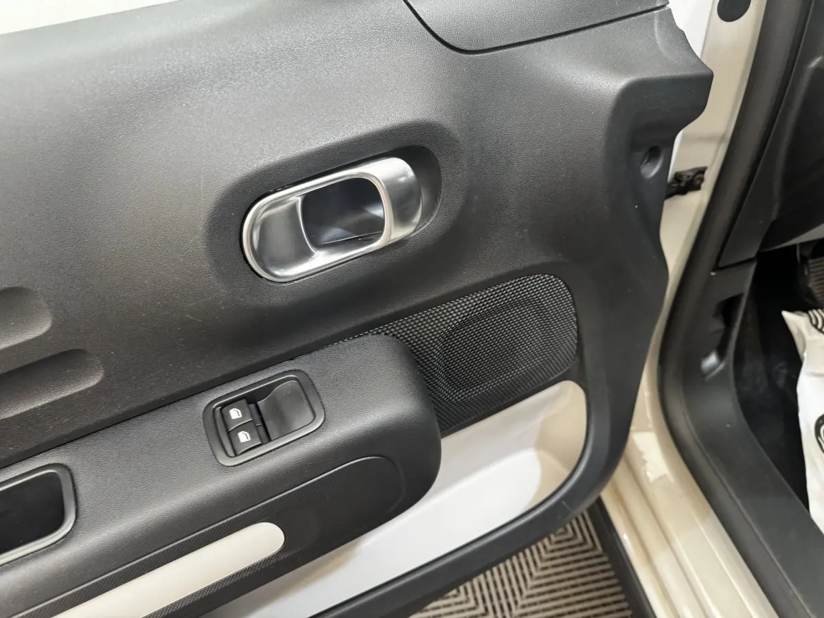 Vue rapprochée de la porte avant gauche beige d'une Citroën C3 2021 avec poignée intérieure chromée et commandes de vitres.