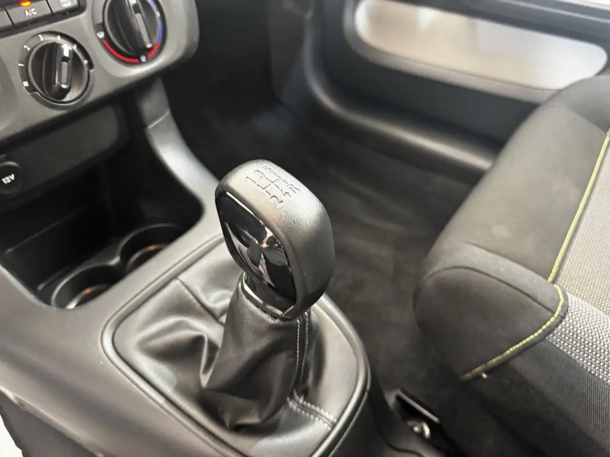 Gros plan sur le levier de vitesses manuel noir dans l’habitacle d’une Citroën C3 beige, avec console et siège partiellement visibles.