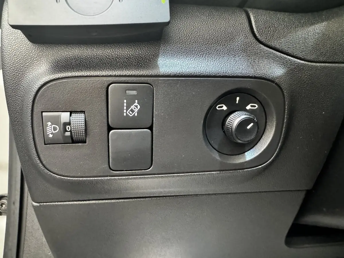 Vue rapprochée des commandes de réglage des phares et des rétroviseurs sur une Citroën C3 beige 2021.