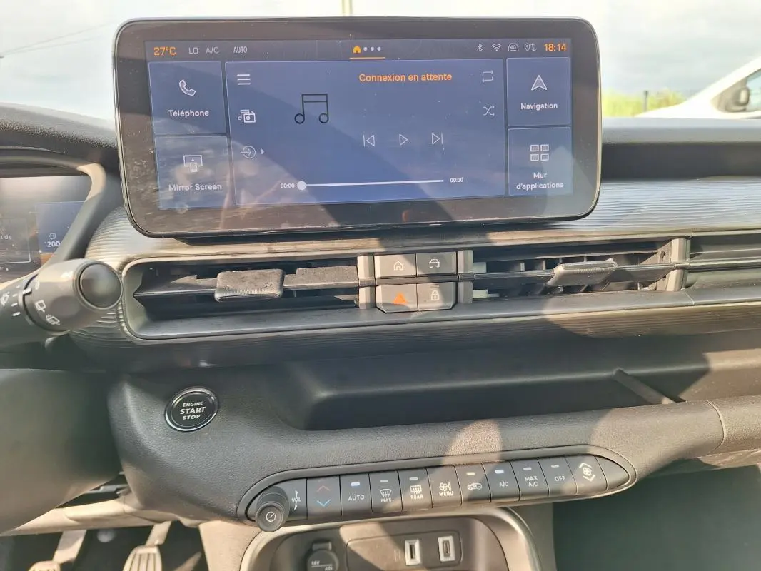 Vue intérieure du tableau de bord du Jeep Avenger 2025 avec écran tactile central et commandes climatisation automatique.