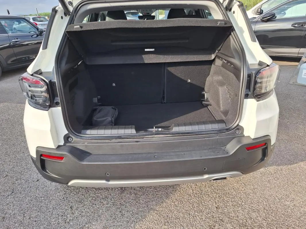 Vue arrière ouverte du coffre d'un Jeep Avenger blanc 2025, soulignant l'espace de chargement et les feux arrière LED.