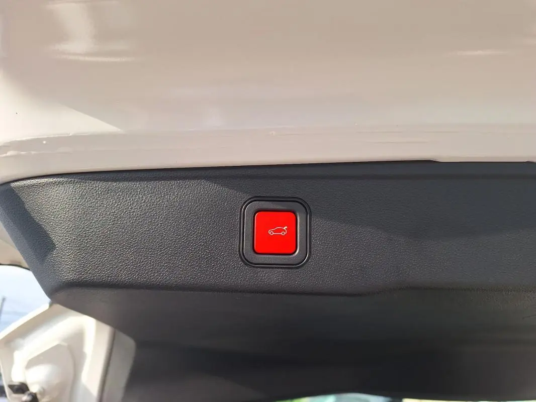 Bouton rouge d'ouverture électrique du coffre sur la partie intérieure du hayon blanc du Jeep Avenger 2025.