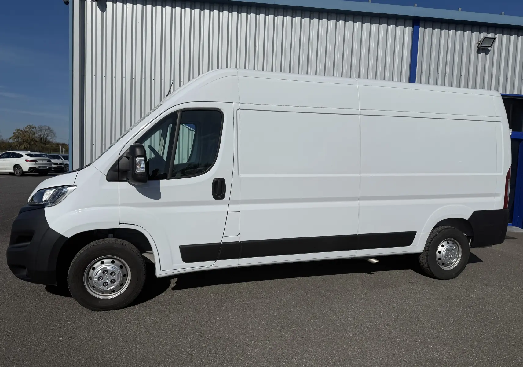 Vue de profil côté gauche d’un Opel Movano Fourgon blanc 2023 avec porte latérale coulissante et jantes acier.