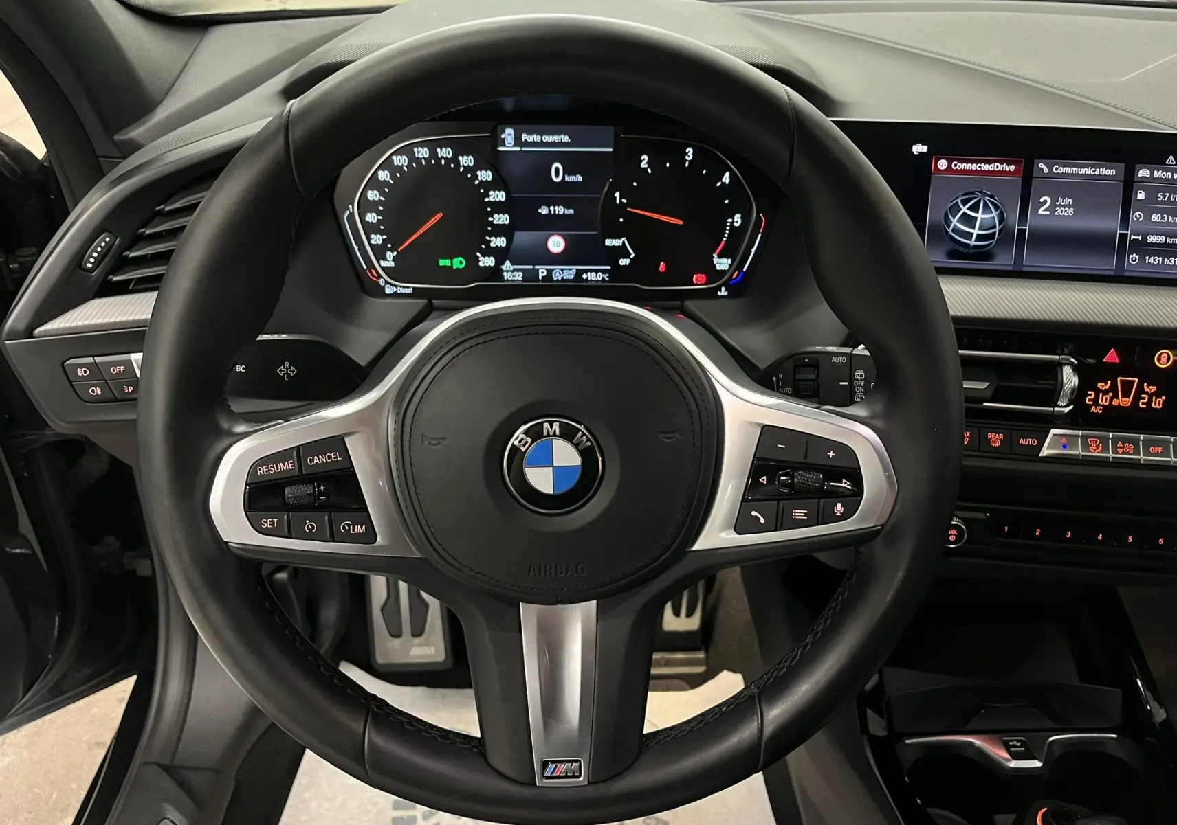 Vue rapprochée du volant M Sport noir avec commandes intégrées et tableau de bord numérique d'une BMW Série 1 F40.