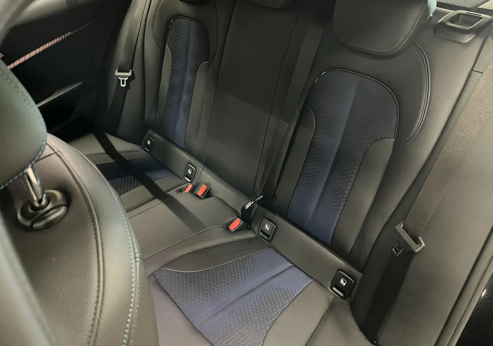 Vue intérieure sur la banquette arrière cuir noir et bleu avec ceintures et fixations ISOFIX d'une BMW Série 1 F40.