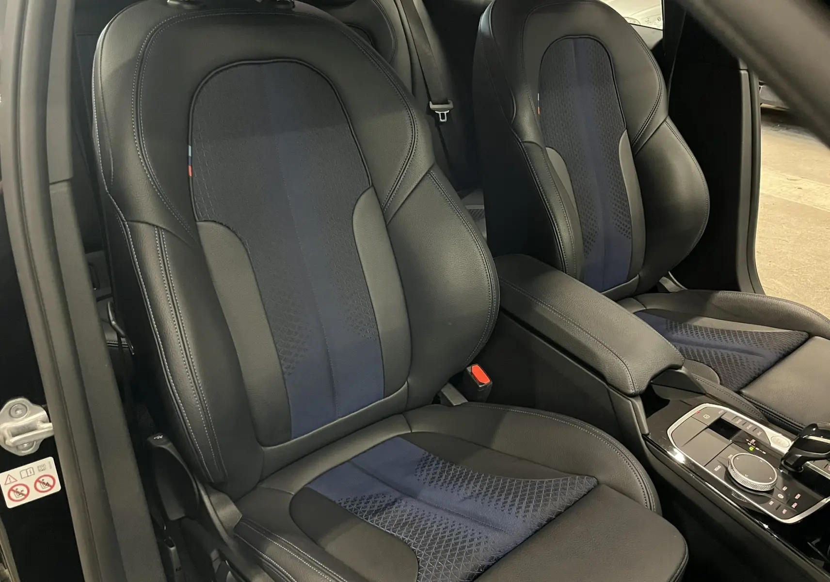Vue intérieure rapprochée des sièges avant sport en cuir noir avec inserts bleus de la BMW Série 1 F40 118dA M Sport.