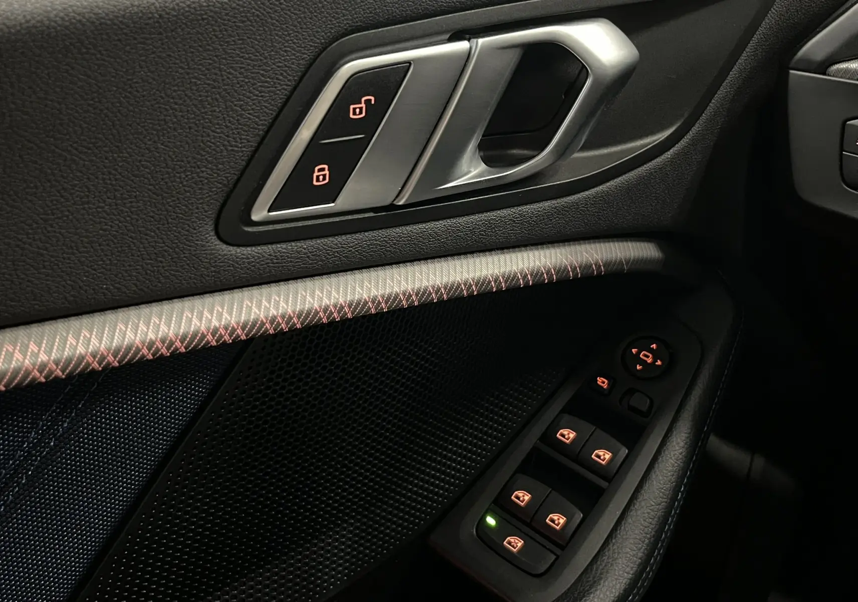 Gros plan sur la porte côté gauche de la BMW Série 1 F40 noire, montrant les commandes de verrouillage et les boutons de lève-vitres.