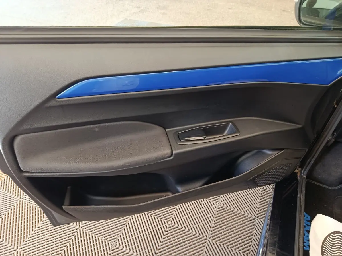 Vue intérieure du panneau de porte côté conducteur de l'AIXAM Ambition 0.5 City Coupe GTI 2023 avec insert bleu et poignée noire.