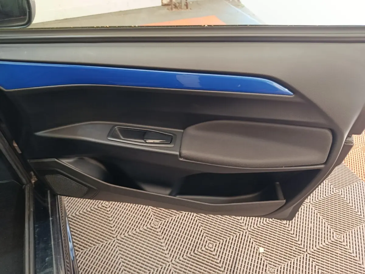 Détail de la porte côté conducteur d'une Aixam Ambition 0.5 City Coupe GTI blanche avec insert bleu, vue intérieure.