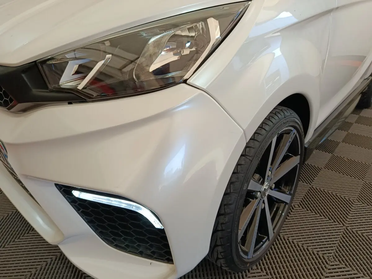 Gros plan sur l'avant droit blanc de l'AIXAM AMBITION 0.5 CITY COUPE GTI 2023, avec phare et jante noire visible.