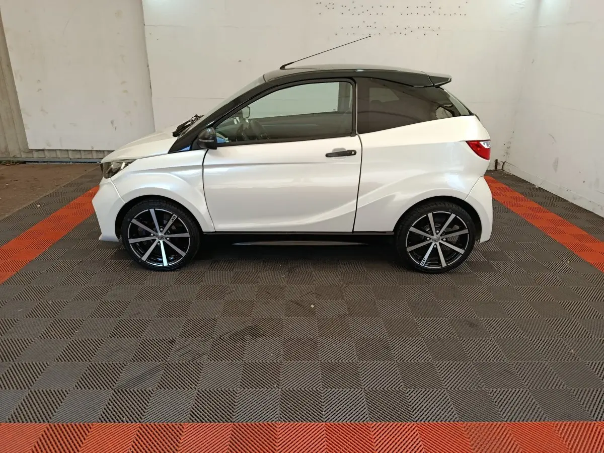 Vue de profil côté gauche d'une Aixam Ambition 0.5 City Coupe GTI blanche avec jantes noires et rétroviseur conducteur noir.