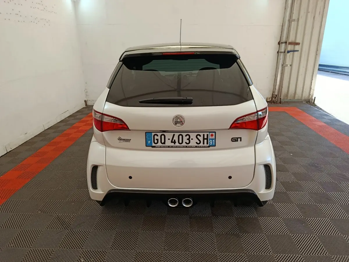 Vue arrière d'une Aixam Ambition 0.5 City Coupe GTI blanche 2023 avec double sortie d'échappement centrale et lunette arrière teintée.