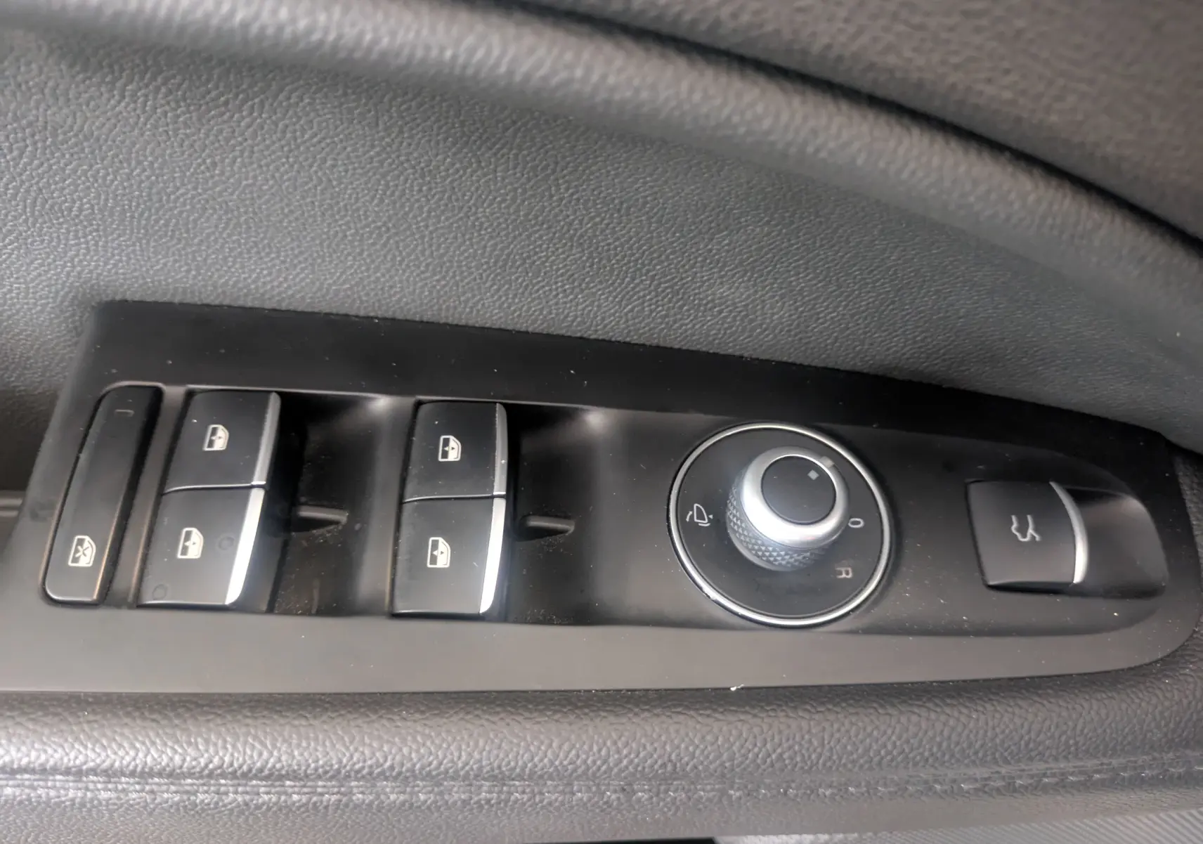 Gros plan sur les commandes de lève-vitres et réglage des rétroviseurs côté conducteur d'un Alfa Romeo Stelvio blanc 2023.