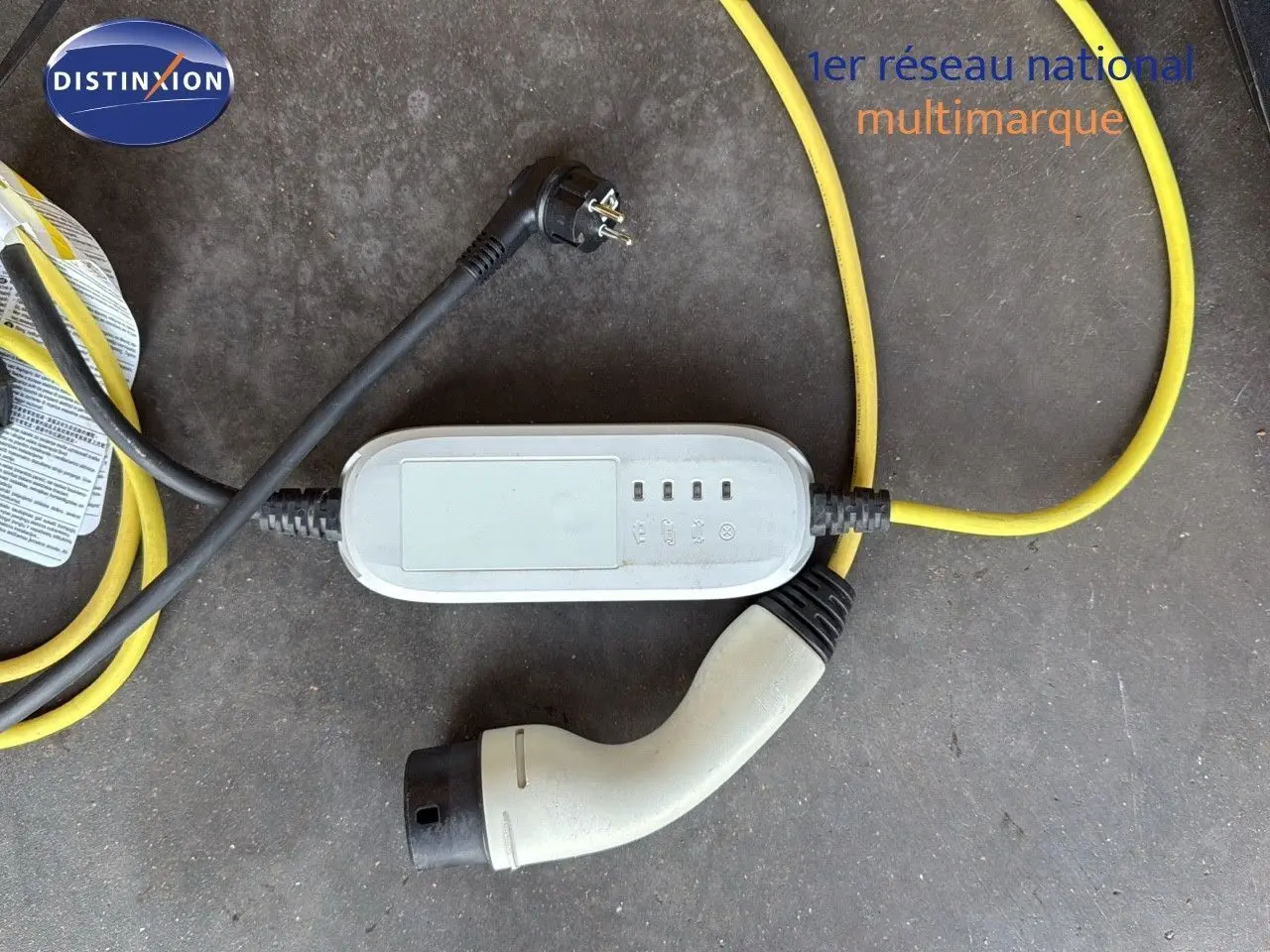 Câble de recharge hybride avec prise blanche et câble jaune sur sol gris, accessoire du CUPRA Formentor noir minuit.