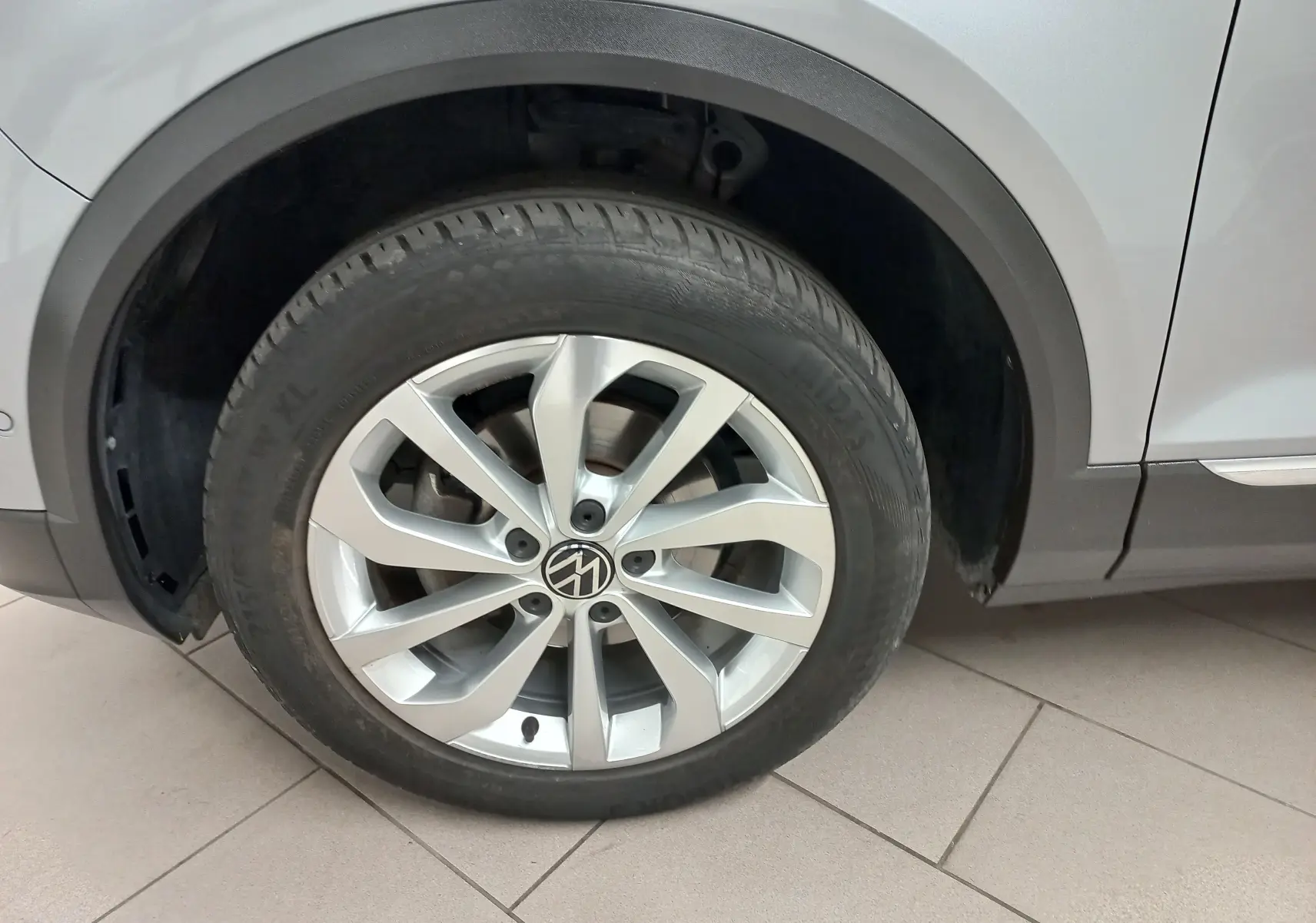 Gros plan sur la roue avant droite du Volkswagen T-Roc gris pyrite avec jante alliage et passage de roue noir.