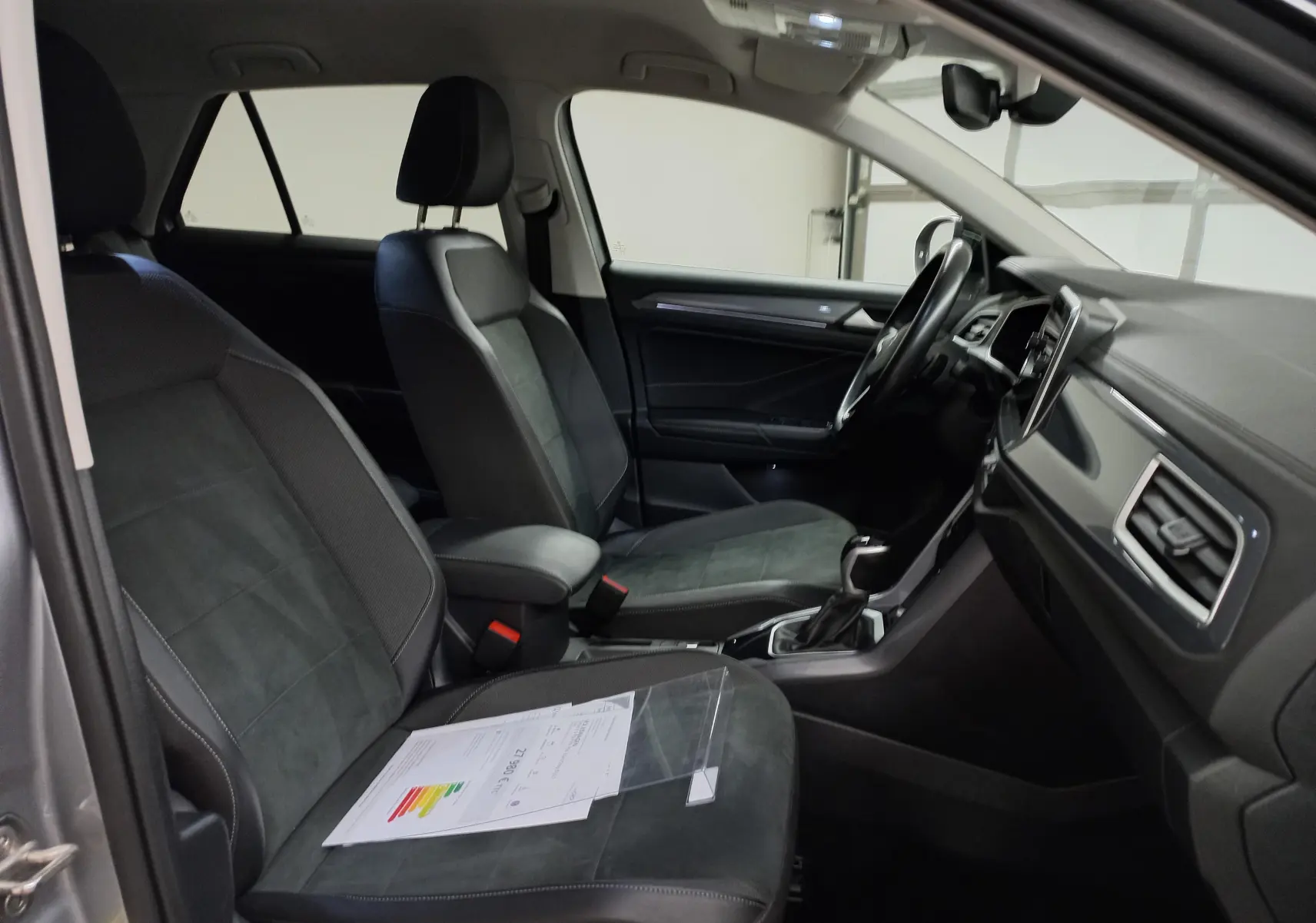 Vue intérieure côté conducteur du Volkswagen T-Roc 1.5 TSI 150 DSG7 Style 2023 avec sièges noirs et tableau de bord moderne.