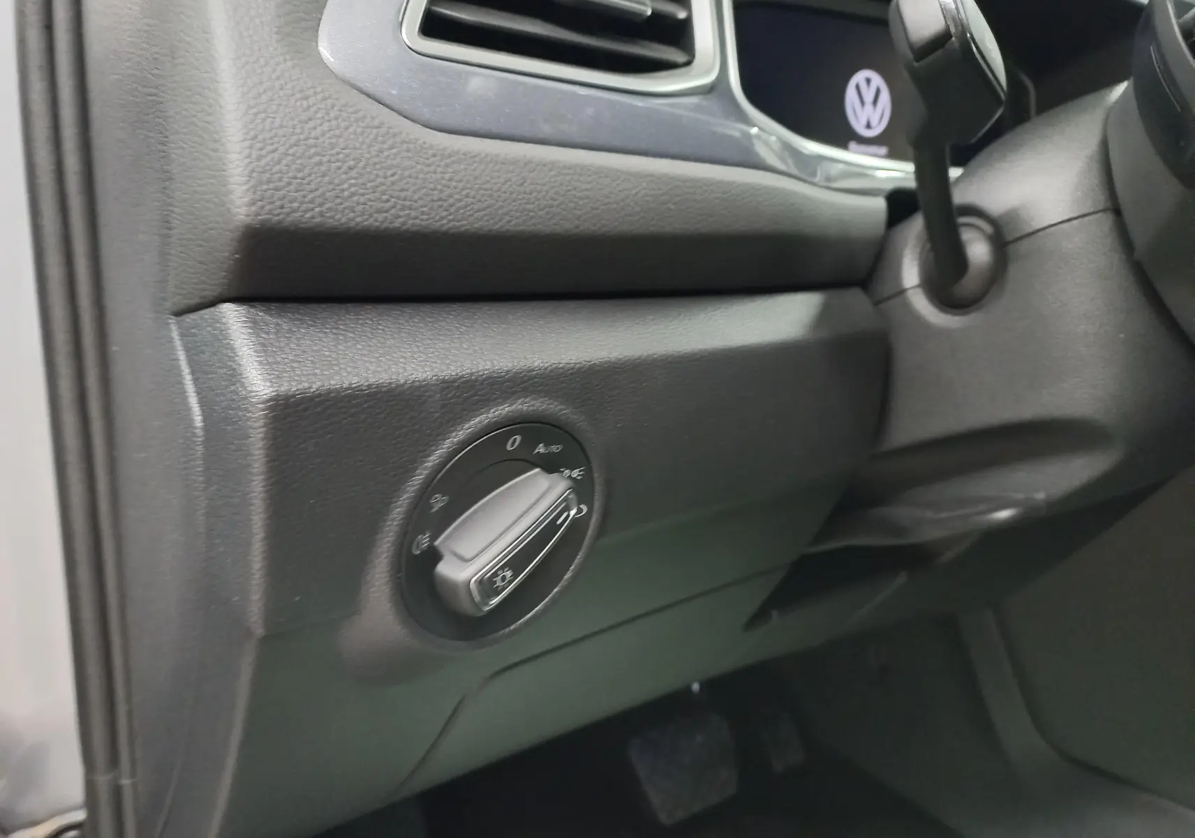 Gros plan sur le bouton de commande des phares côté gauche du tableau de bord du Volkswagen T-Roc gris pyrite 2023.