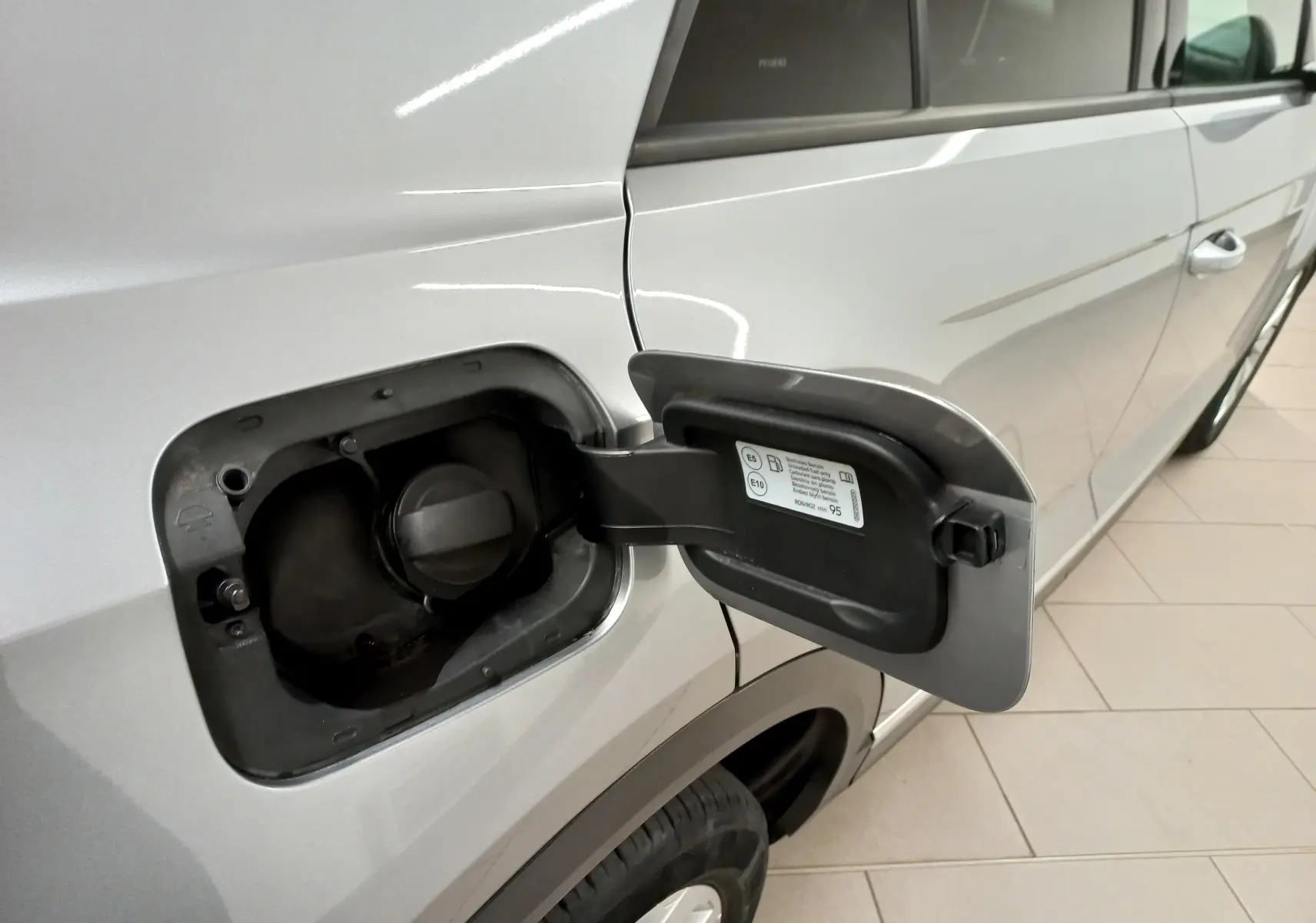 Détail de la trappe à carburant ouverte côté gauche sur un Volkswagen T-Roc gris Pyrite toit noir 2023.