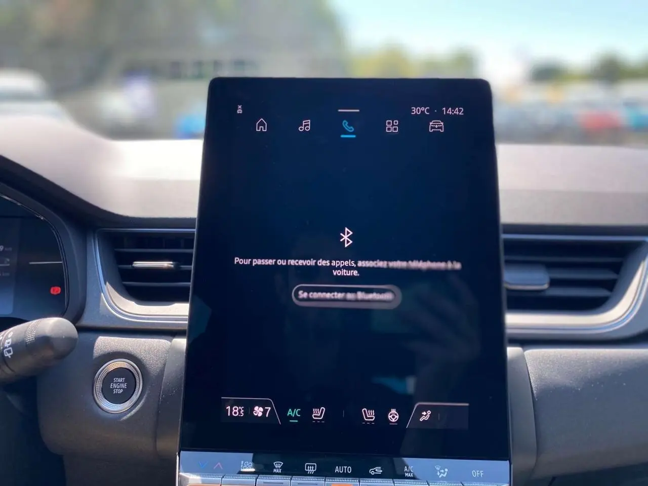 Vue rapprochée de l'écran tactile central du Renault Captur gris Cassiopée, affichant les commandes de climatisation et connectivité.