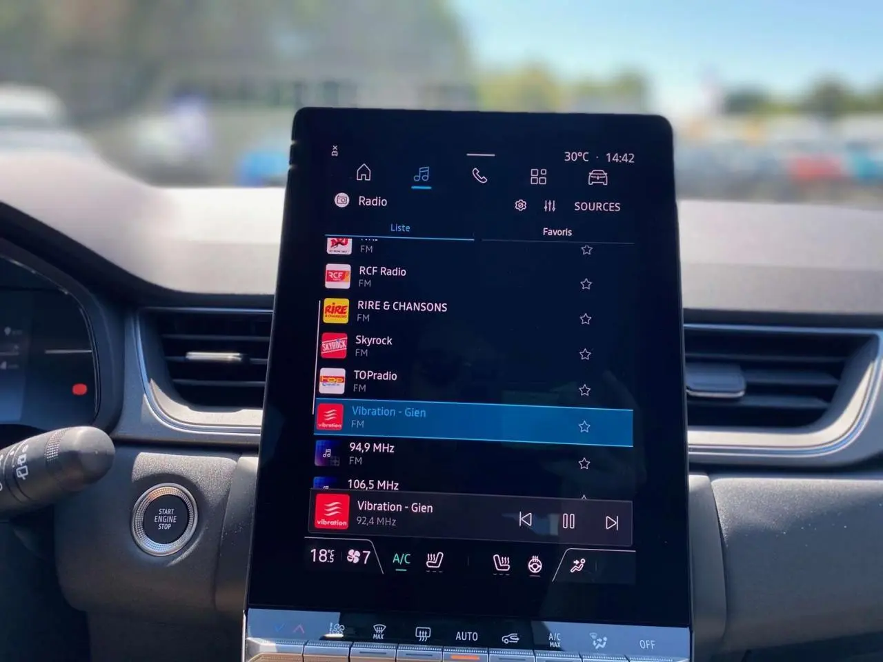 Écran tactile central allumé affichant la radio dans l’habitacle du Renault Captur gris Cassiopée toit noir.