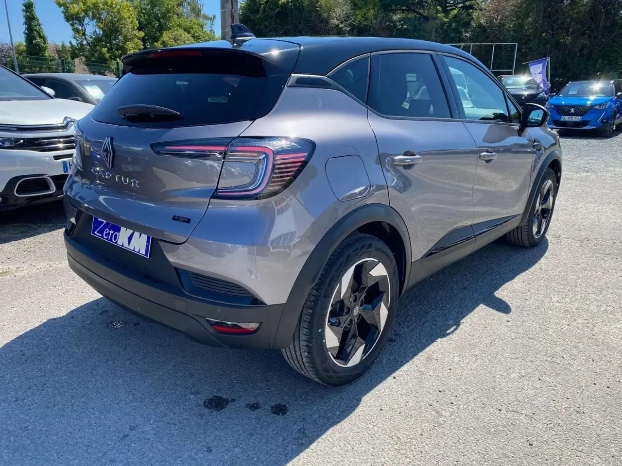 Vue 3/4 arrière droite du Renault Captur 2025 gris Cassiopée avec toit noir et jantes noires distinctives.