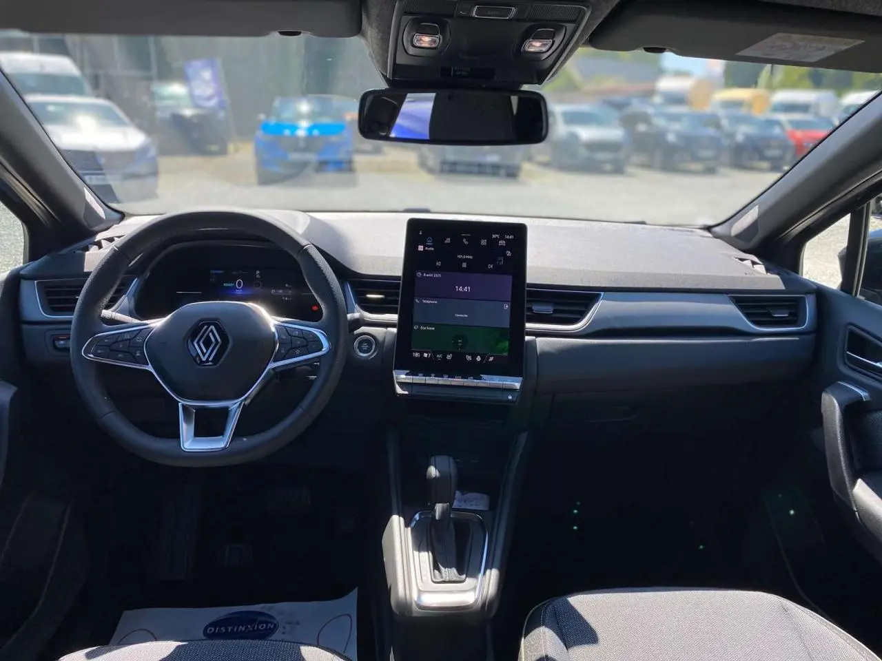 Vue intérieure du tableau de bord et volant Renault Captur 2025 avec écran tactile vertical et levier de boîte automatique.