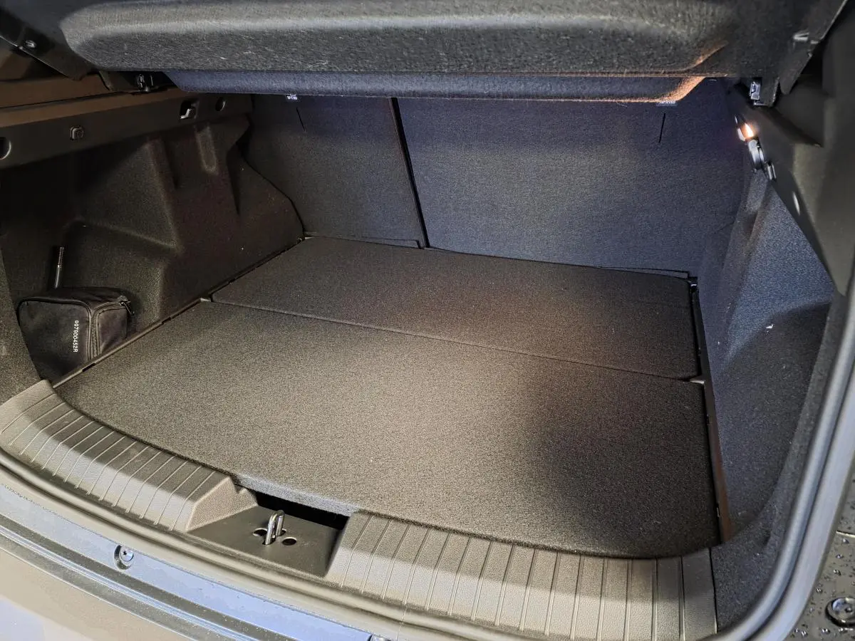 Coffre ouvert du Dacia Duster 1.6 Hybrid noir, montrant un espace de chargement plat et bien éclairé.