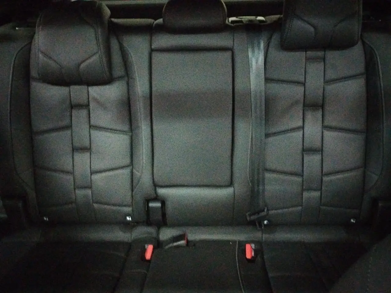 Vue rapprochée de la banquette arrière en cuir noir Basalte du DS7 2025, avec appuie-tête et ceintures visibles.