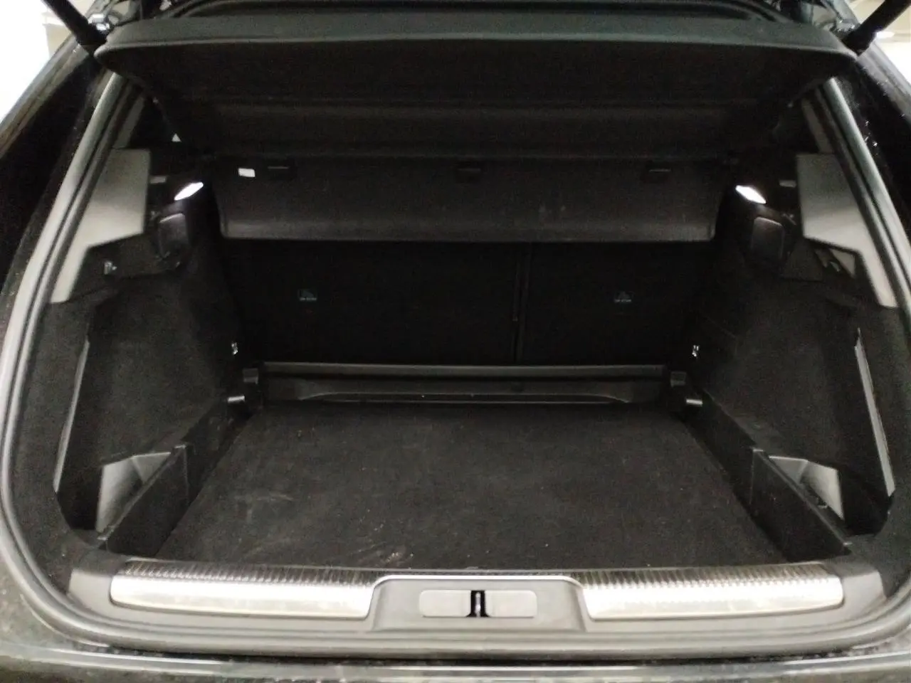 Coffre ouvert vu de l'arrière d'un DS7 noir Perla, montrant un espace de chargement spacieux et propre.