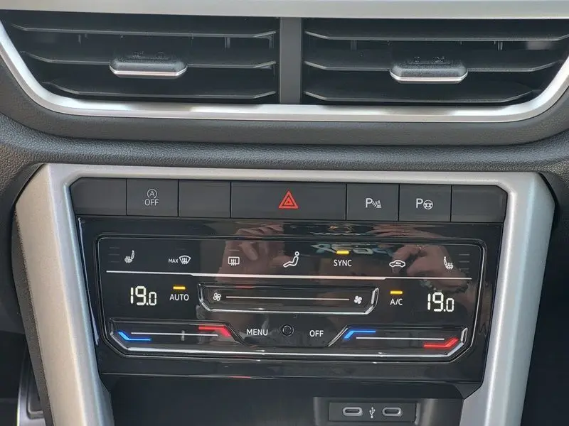 Vue rapprochée du tableau de bord du Volkswagen T-Roc 2025, montrant la commande de climatisation digitale avec affichage 19°C.