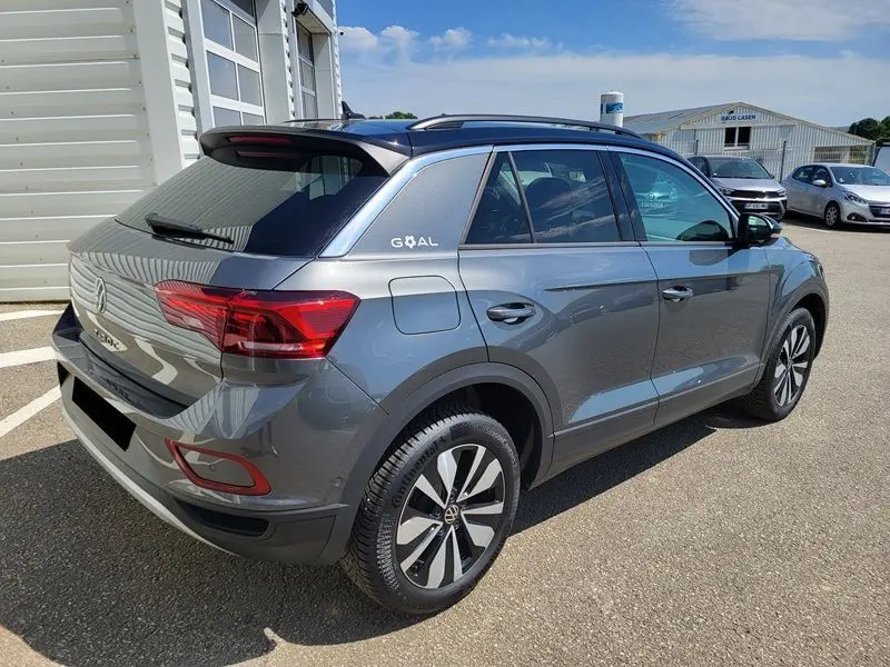 Volkswagen T-Roc gris Indium en 3/4 arrière droit, avec jantes alliage et attelage amovible visible.