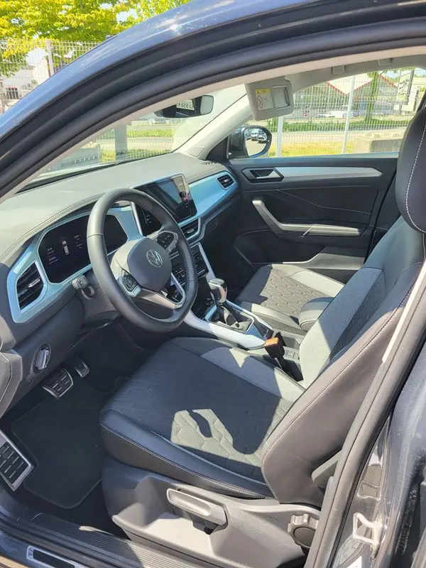 Intérieur côté conducteur du Volkswagen T-Roc gris Indium 2025, montrant tableau de bord et sièges tissu et cuir.