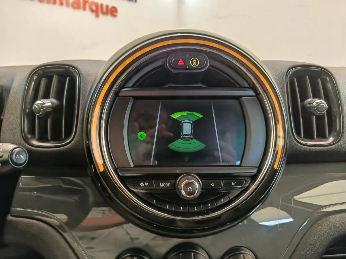 Gros plan sur l’écran central rond du tableau de bord d’une MINI Countryman 2019 noir, affichant l’aide au stationnement.