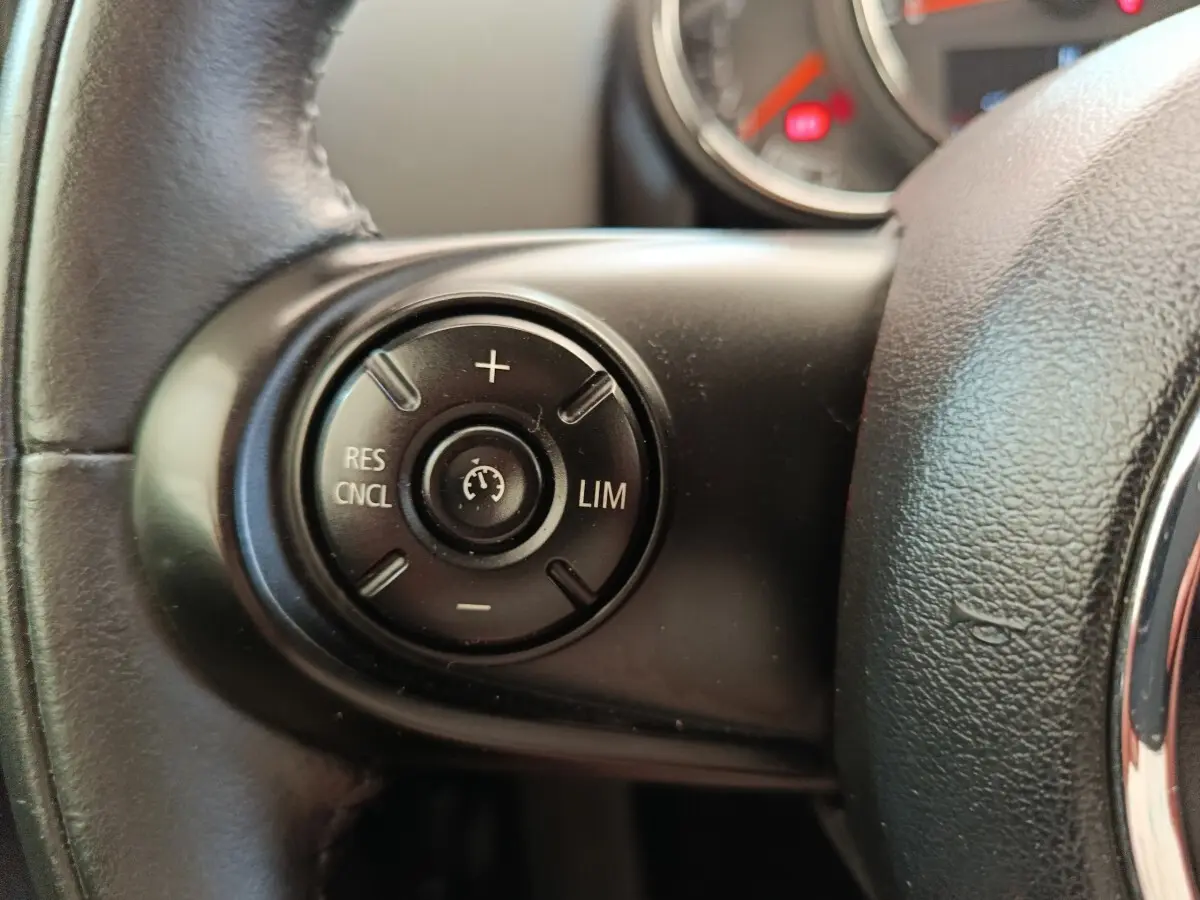 Gros plan sur la commande de régulateur de vitesse au volant cuir noir d'une MINI Countryman 2019.