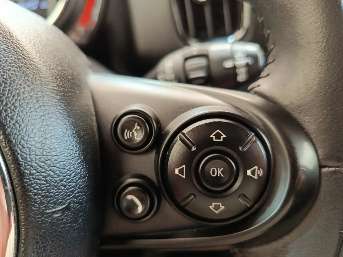 Gros plan sur les commandes multifonctions noires du volant cuir d'une MINI Countryman noir, côté gauche.