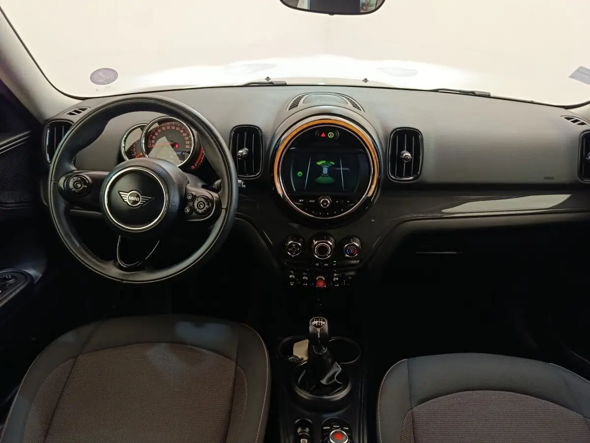 Vue intérieure avant du tableau de bord noir de la MINI Countryman Cooper 2019 avec volant cuir et écran central rond lumineux.