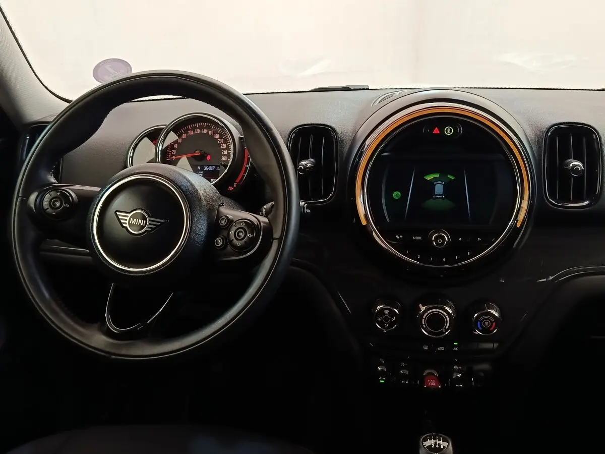Vue intérieure centrée sur le volant cuir et le tableau de bord numérique circulaire d'une MINI Countryman noire de 2019.