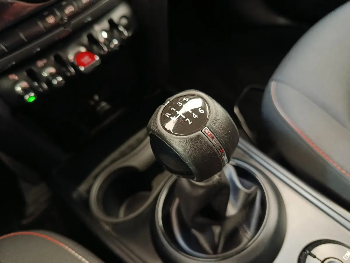 Gros plan sur la commande de boîte manuelle 6 vitesses de la MINI Countryman noire, avec console et siège partiellement visibles.